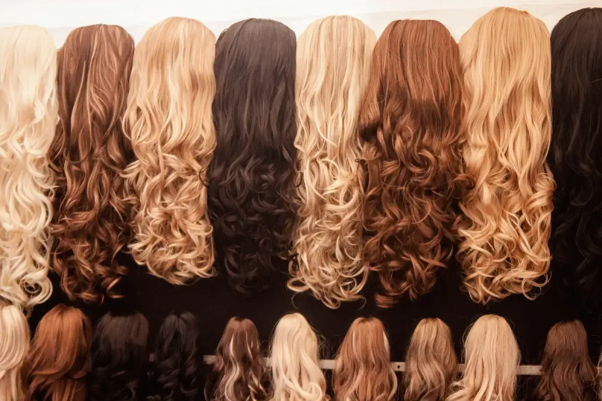 Various long, wavy hair extensions in multiple colors displayed on mannequin heads.