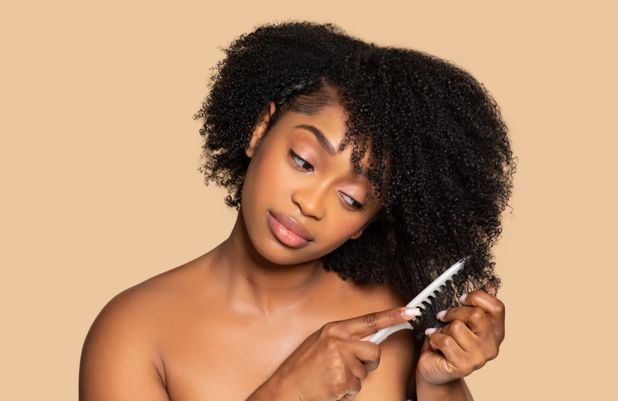 Woman gently combing her curly hair with focus.