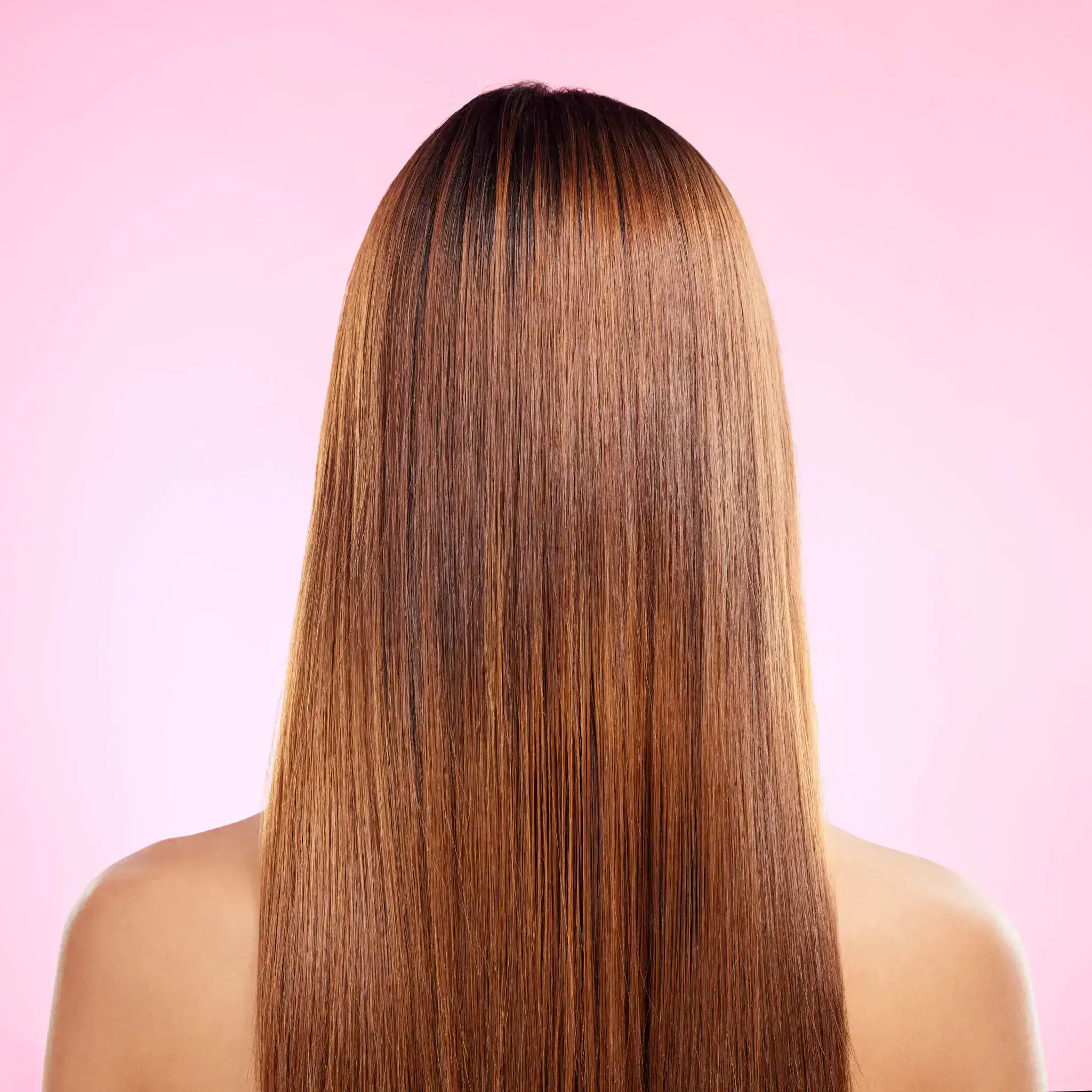 Back view of a person with long, straight brown hair against a pink background.